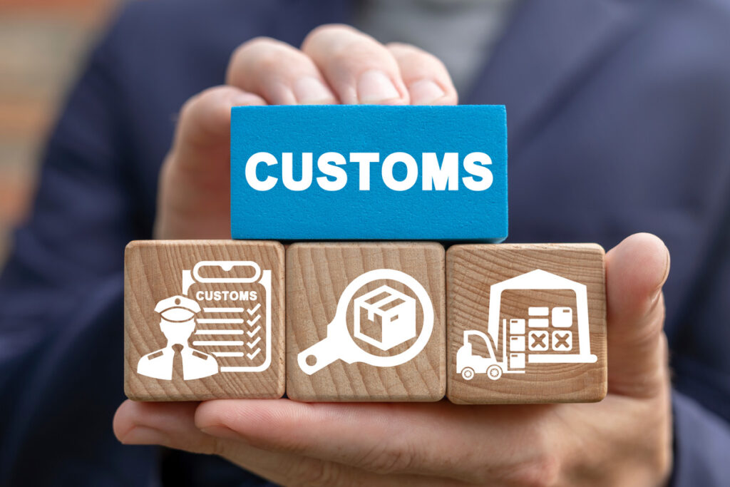 A person’s hands holding a blue wooden block that reads “CUSTOMS” and brown blocks with custom images in El Paso.